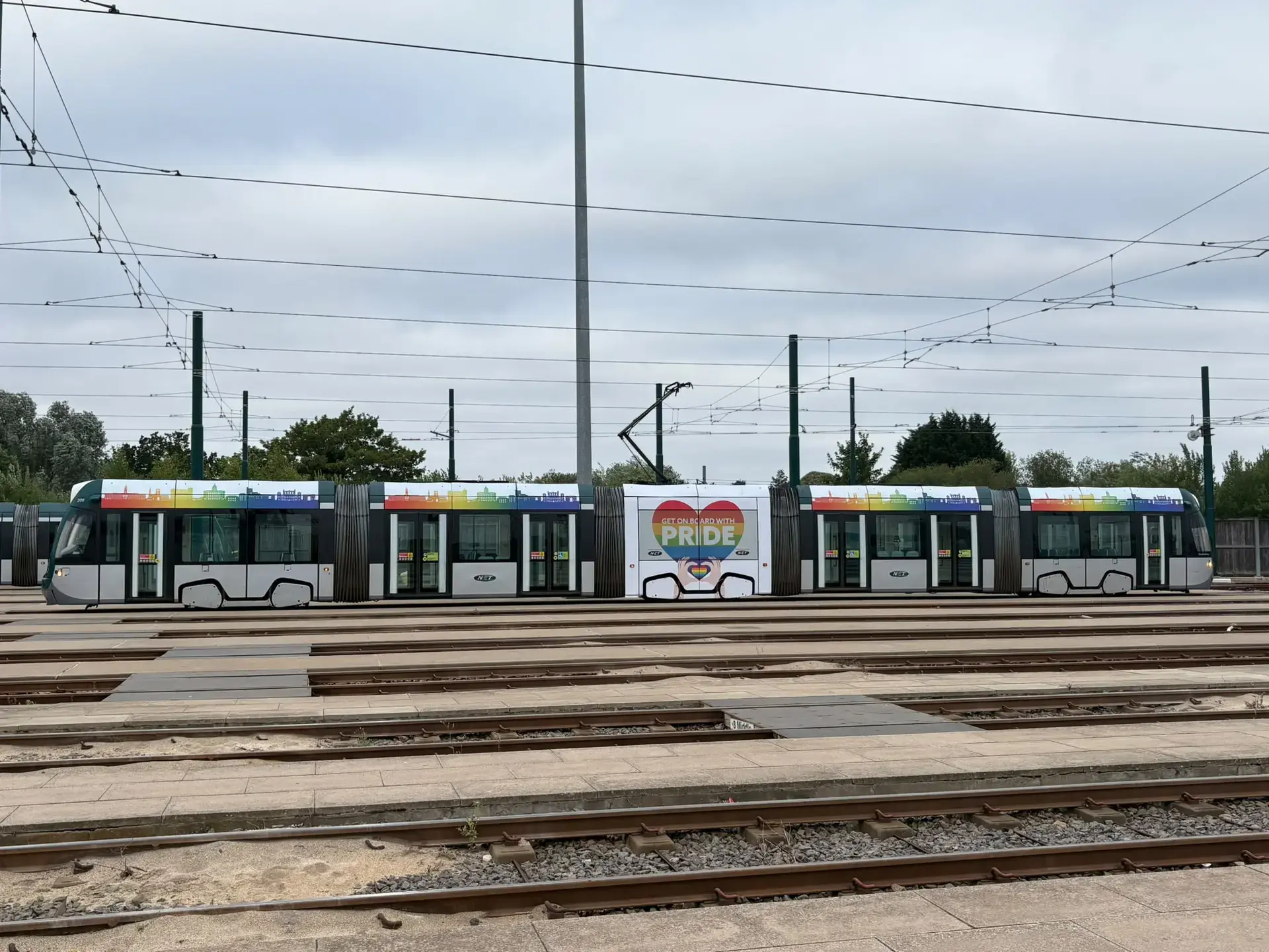 NET's rainbow Pride tram at the depot in Nottingham, decorated with a rainbow city skyline and a 'Get on board with Pride' heart design.